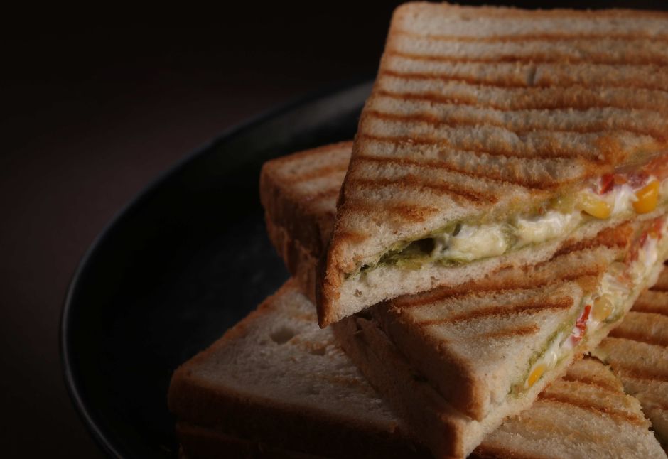 Close-up of a toasted sandwich filled with vegetables and cheese on a plate.