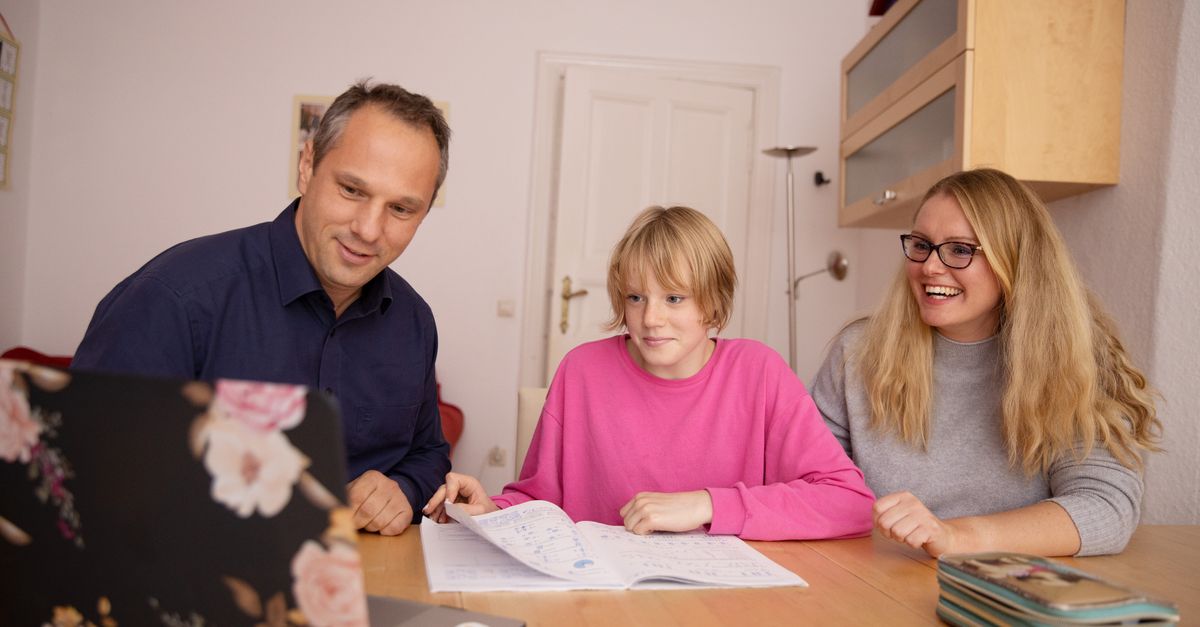 Family engaged in online learning together at home using laptop, focusing on education and connection.