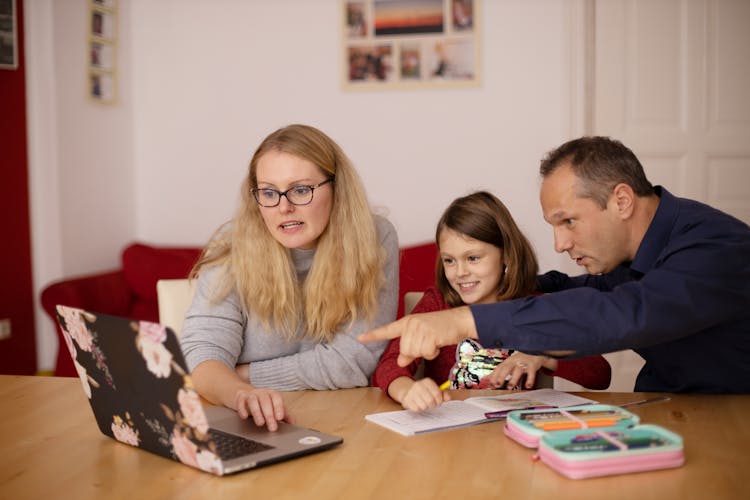 Parents Helping Their Daughter In Her Online Classes