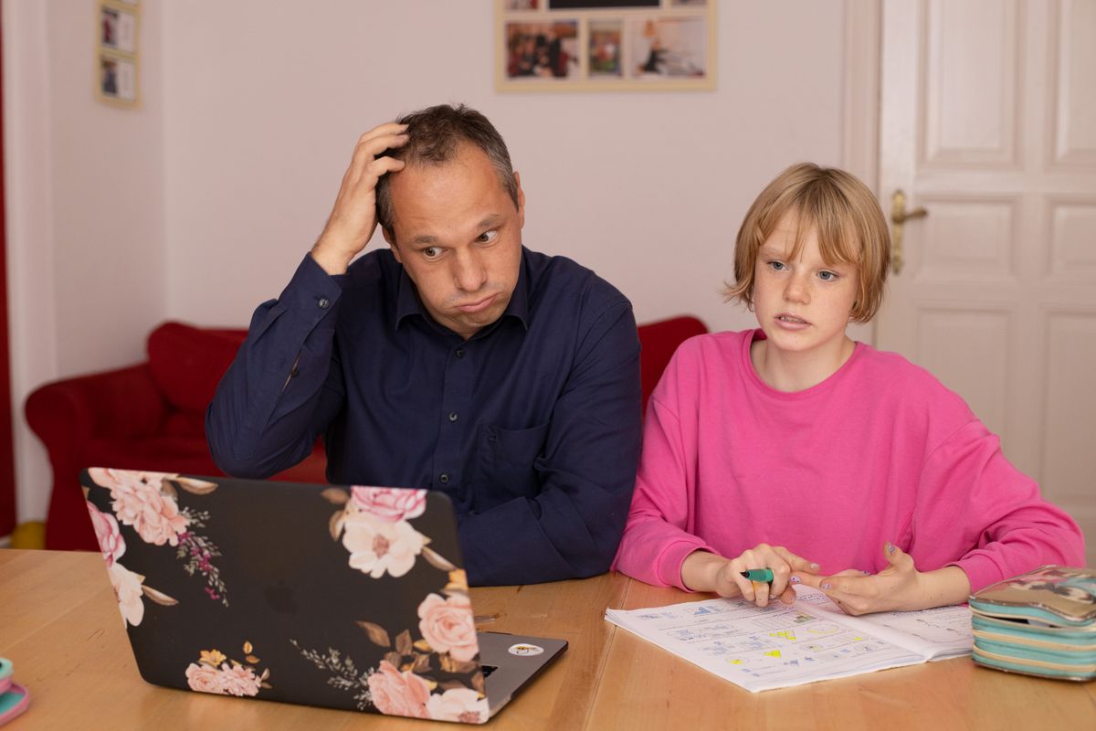 Een ouder en een kind zoeken samen naar uitleg bij het schoolwerk