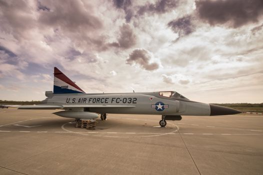 A historical U.S. Air Force fighter jet displayed on an outdoor airfield with a vibrant sky.