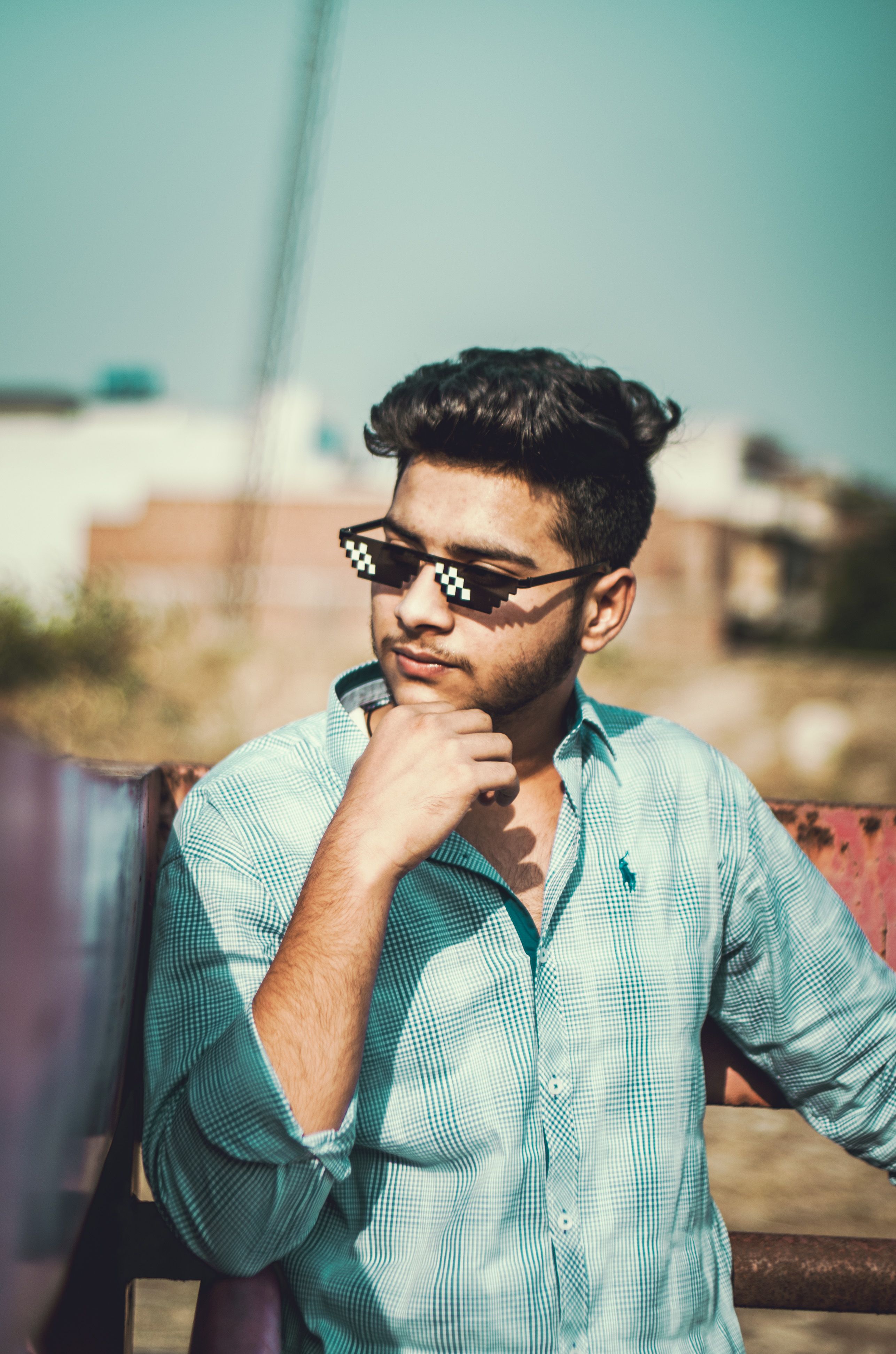 Portrait of a young man posing with pixelated sunglasses in a casual outdoor setting.