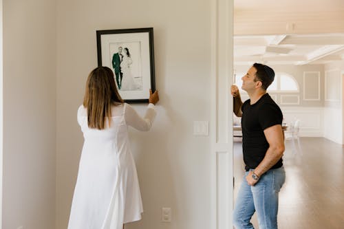 A Woman Hanging a Picture Frame on a Wall · Free Stock Photo