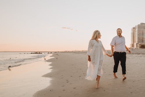 Free Couple Holding Hands While Walking Near the Seashore  Stock Photo