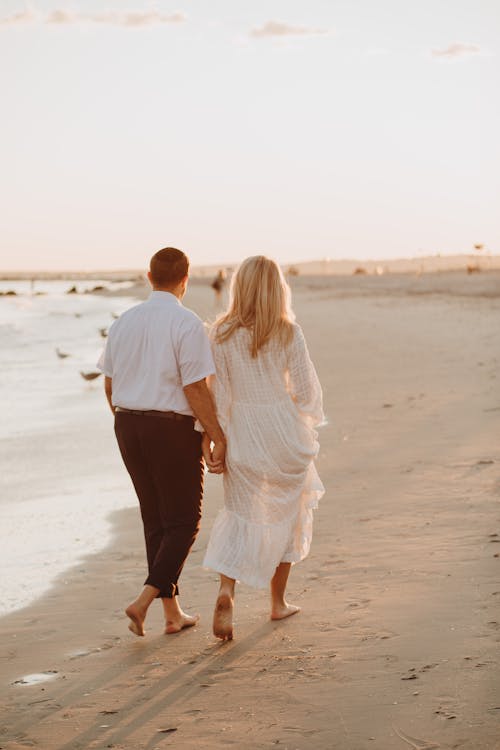 Free Man and Woman Walking on the Beach Stock Photo