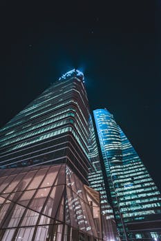 Low angle shot of illuminated skyscrapers against night sky showcasing modern urban architecture.