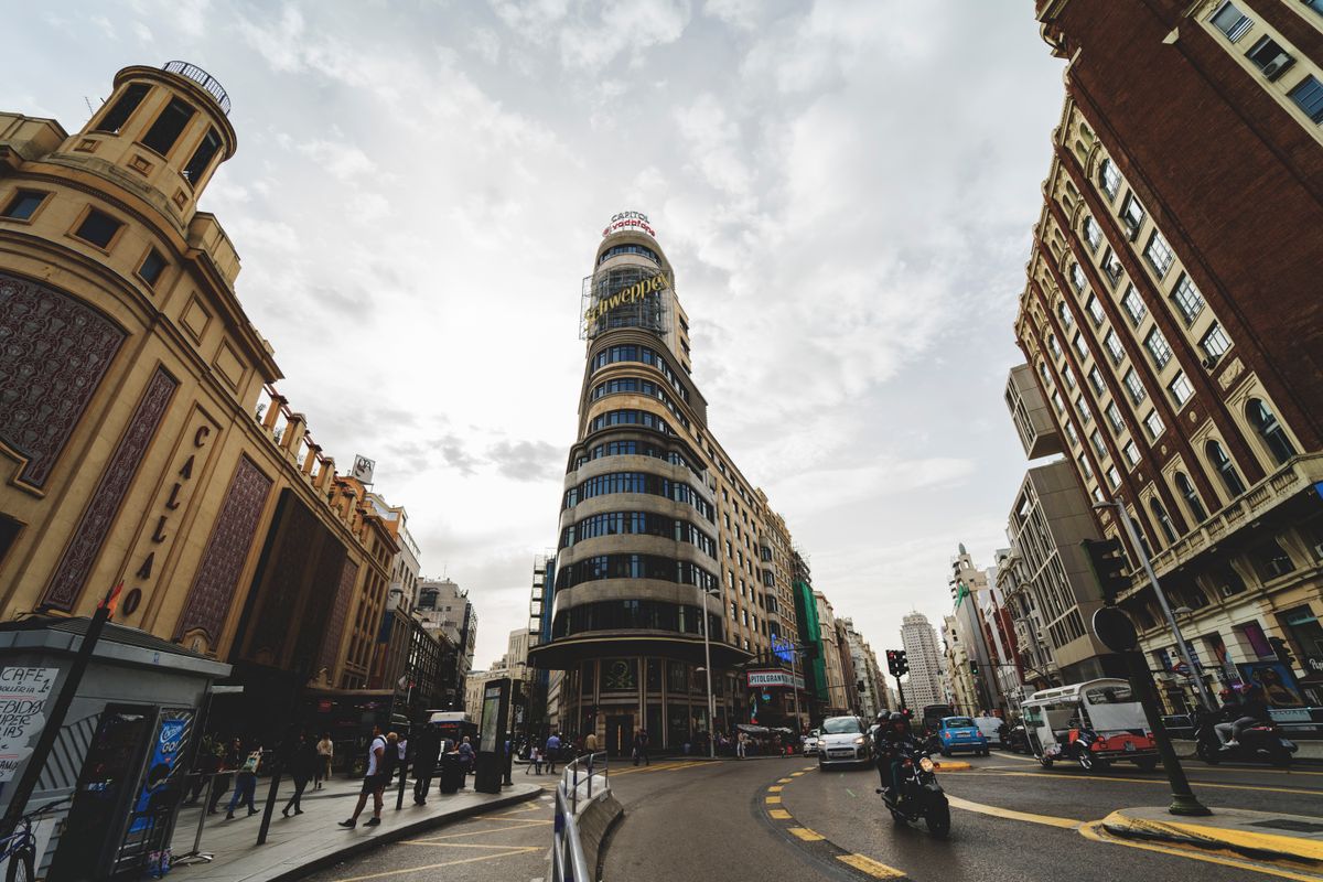 Low angle view of the famous Edificio Capitol in Madrid, bustling city life around.