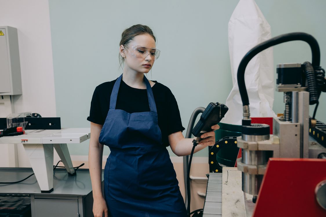 Woman in Blue Apron Using a Machine in the Shop · Free Stock Photo