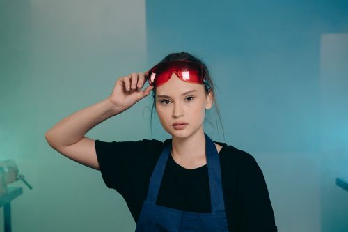 Free A woman in an apron wearing red safety glasses in an indoor setting. Stock Photo