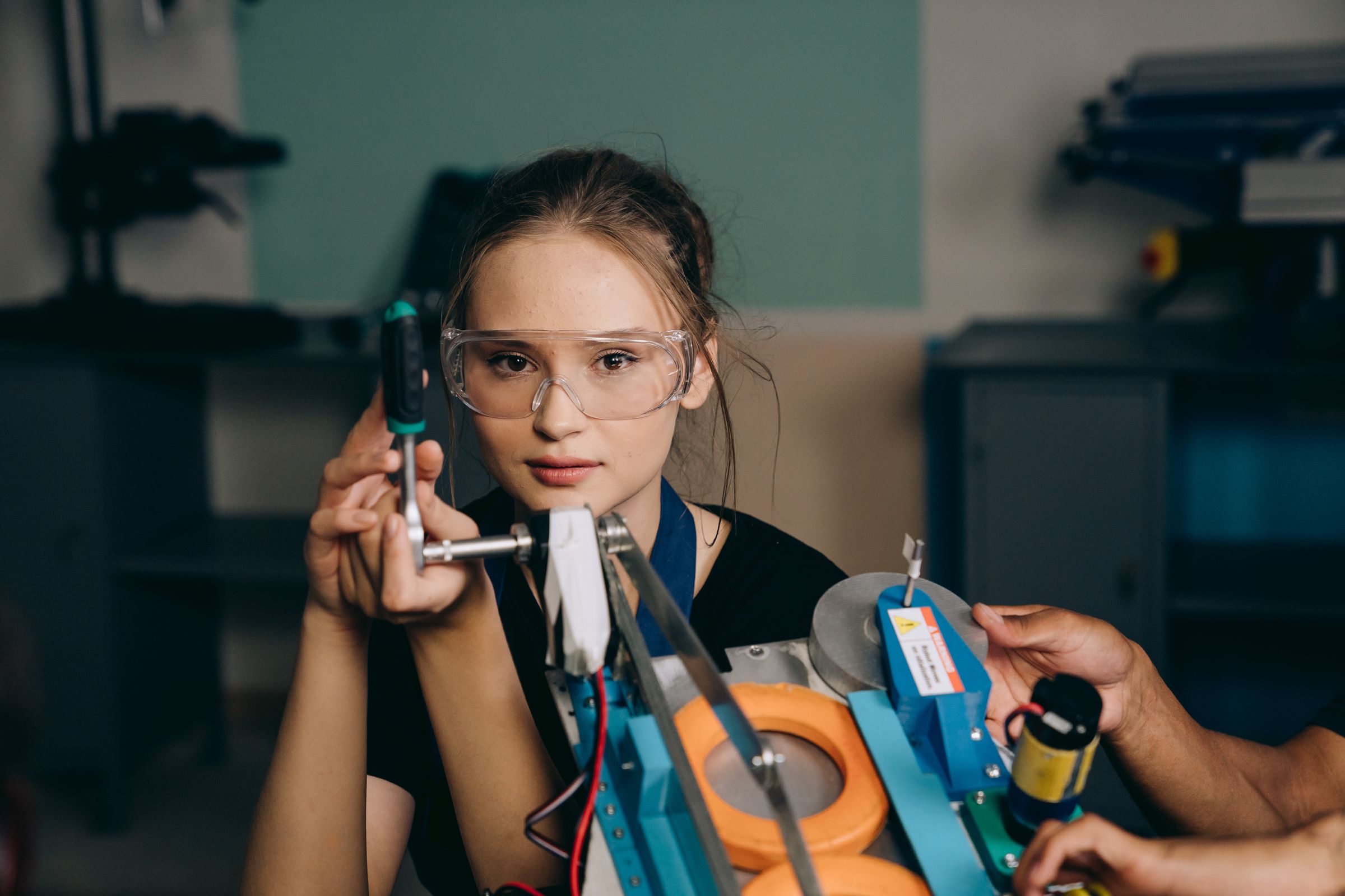 Woman wearing protective goggles while using a hand tool during practical workshop training