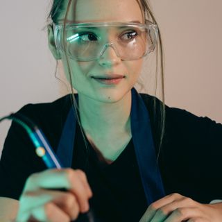 Élodie Vasseur Portrait d'une technicienne en lunettes de protection soudant un composant électronique