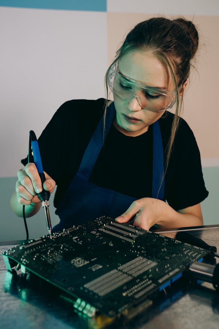 Woman In Goggles Sitting And Working On Computer Hardware