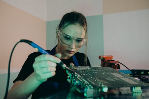 A Woman Using a Soldering on a Circuit Board