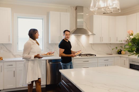 A joyful couple prepares food in a bright, modern kitchen, enjoying each other's company.