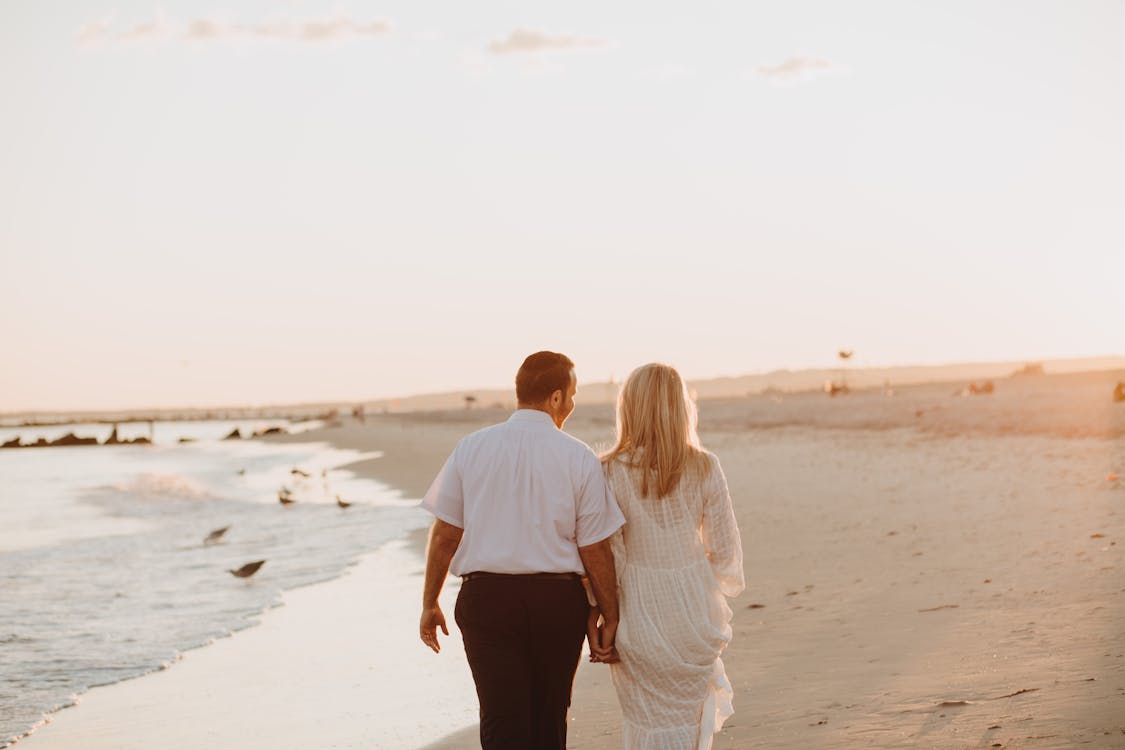 Free Man and Woman Walking on the Shore Stock Photo