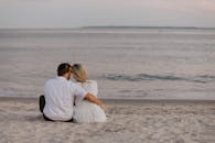 一对夫妇紧紧地坐在海滩上，在日落时拥抱宁静的海景