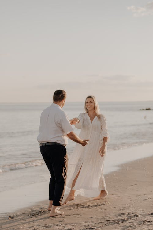 Free Man and Woman Holding Hands on Beach Shore Stock Photo