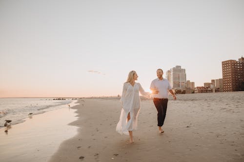 Free Man and Woman Holding Hands on Beach Stock Photo
