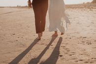 Woman in White Dress Walking on Brown Sand