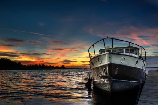 A tranquil scene of a boat docked at sunset with vibrant skies and calm waters.