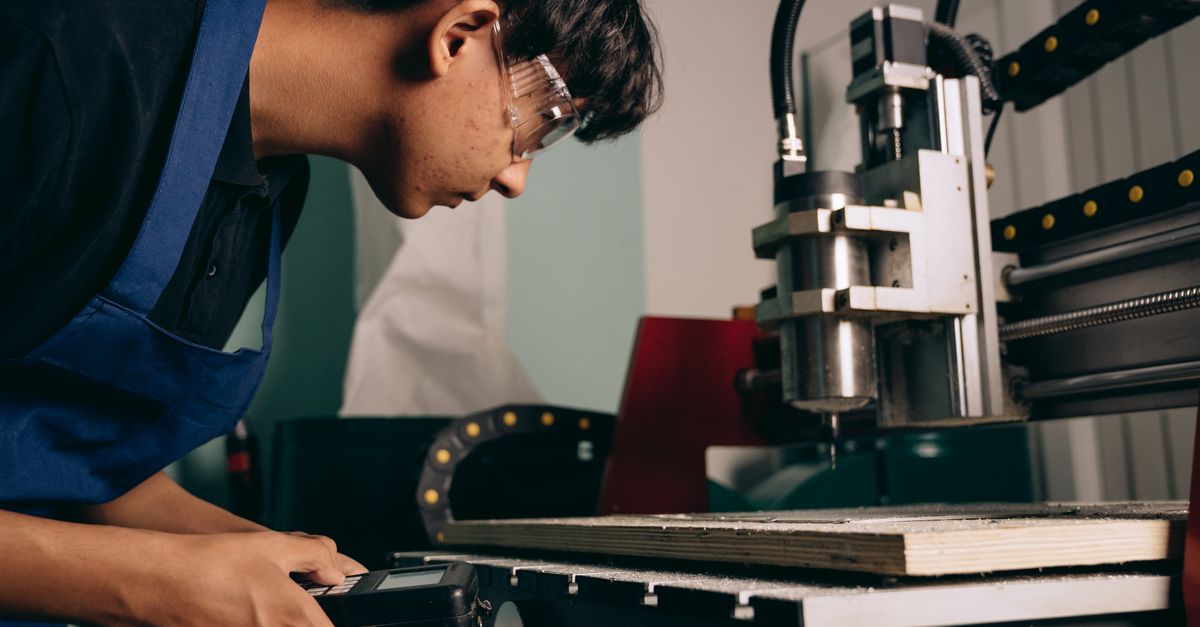 Auszubildender arbeitet an einer Maschine in einer industriellen Ausbildungswerkstatt