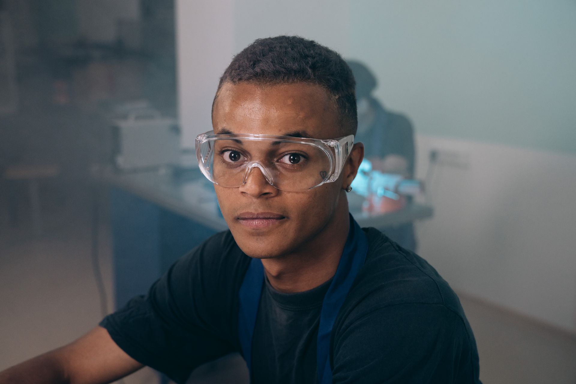 Junge Fachkraft mit Schutzbrille in konzentrierter Arbeitsatmosphäre.