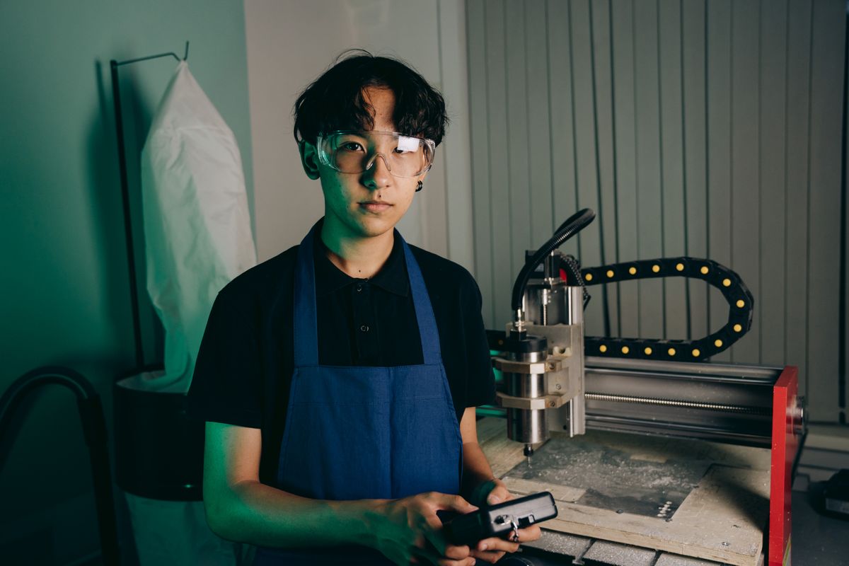 Young engineer operating a CNC machine in an industrial workshop setting