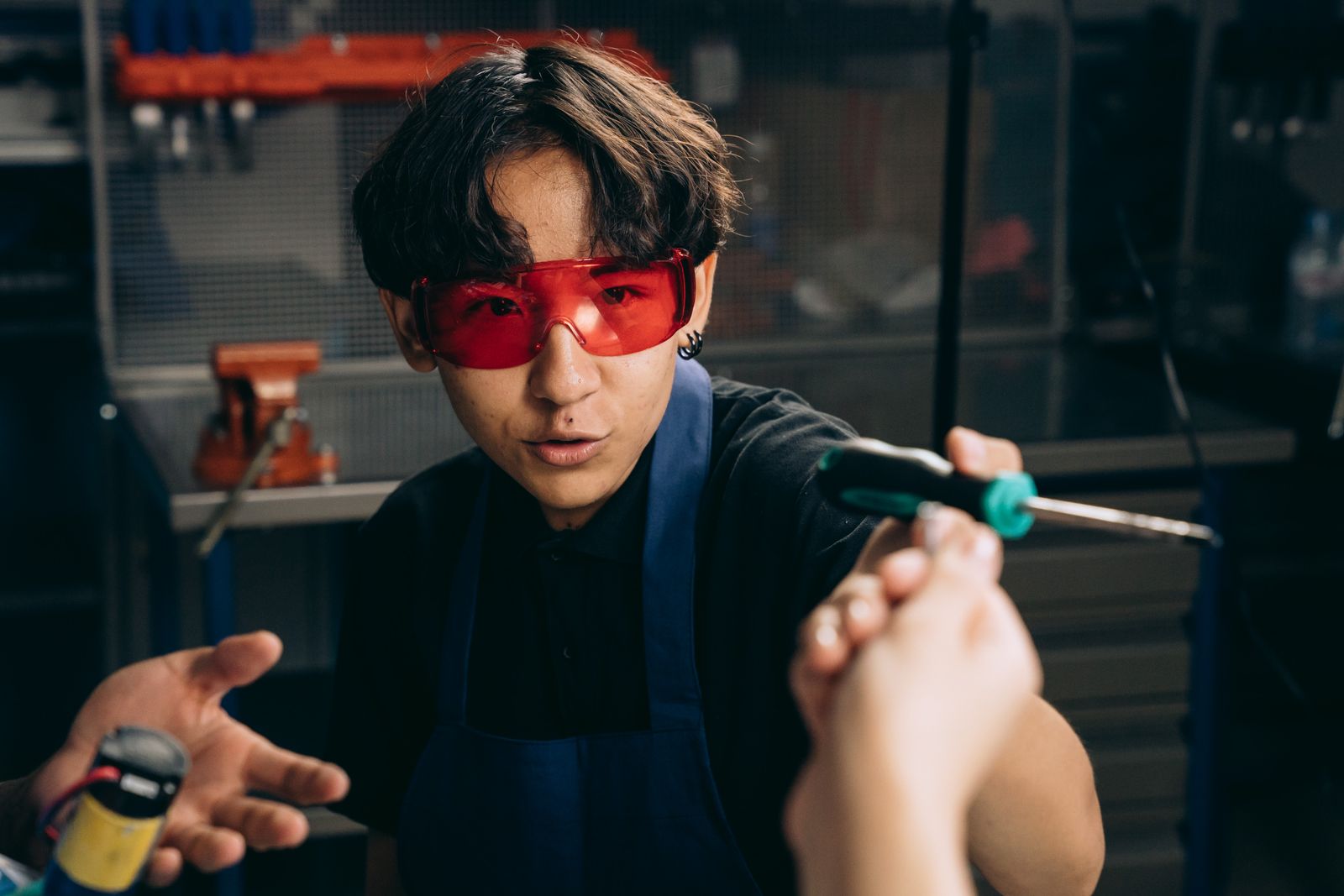 Technician wearing safety glasses holding a screwdriver during a workshop repair task