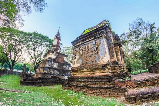 Explore ancient Buddhist ruins in a serene park setting, capturing historic Thai architecture.