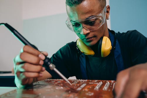 A Man using a Soldering Iron while Working on the Motherboard