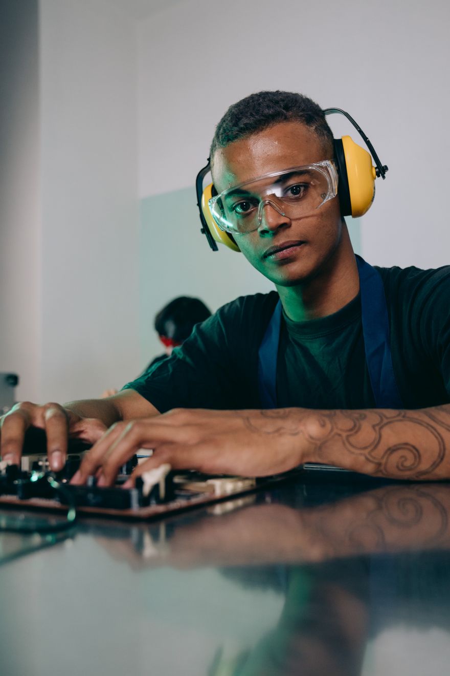 Engineer in safety glasses and ear defenders at a workbench — photo by Mikhail Nilov on Pexels