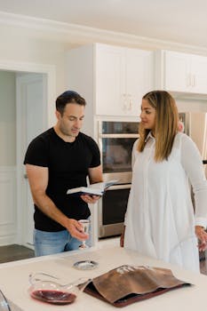 A couple enjoys quality time reading a cookbook in their sleek contemporary kitchen.