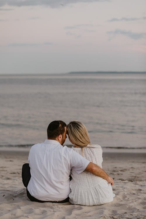 Free Back View of a Couple Sitting on the Sand Stock Photo