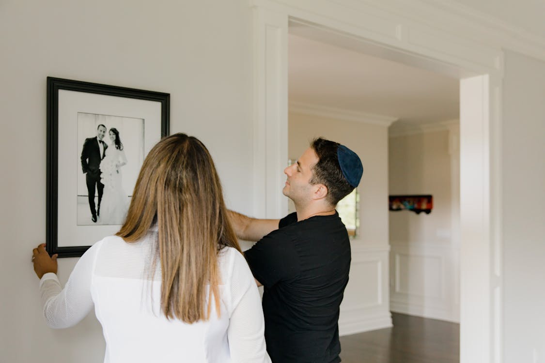 Man and Woman Hanging a Picture Frame on the Wall · Free Stock Photo