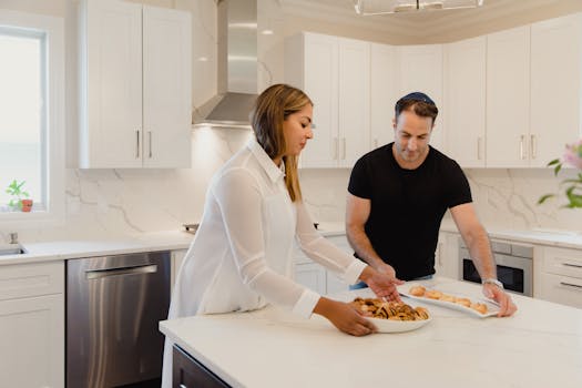A couple prepares pastries together in a bright, modern kitchen setting.
