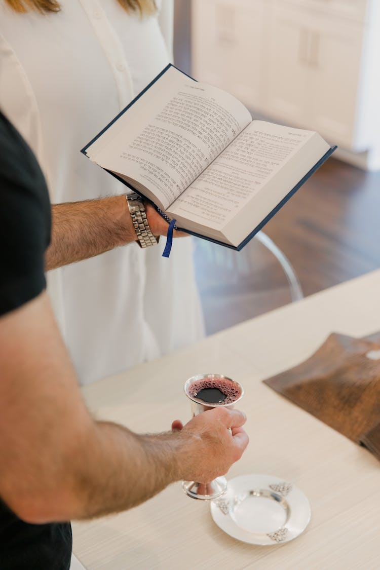 Man Holding Cup And Book