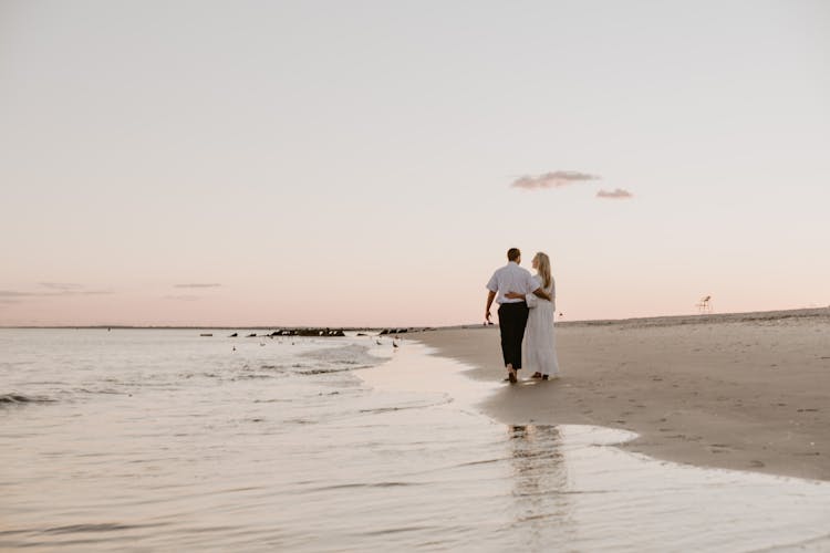 Couple Walking On Beach At Sunset