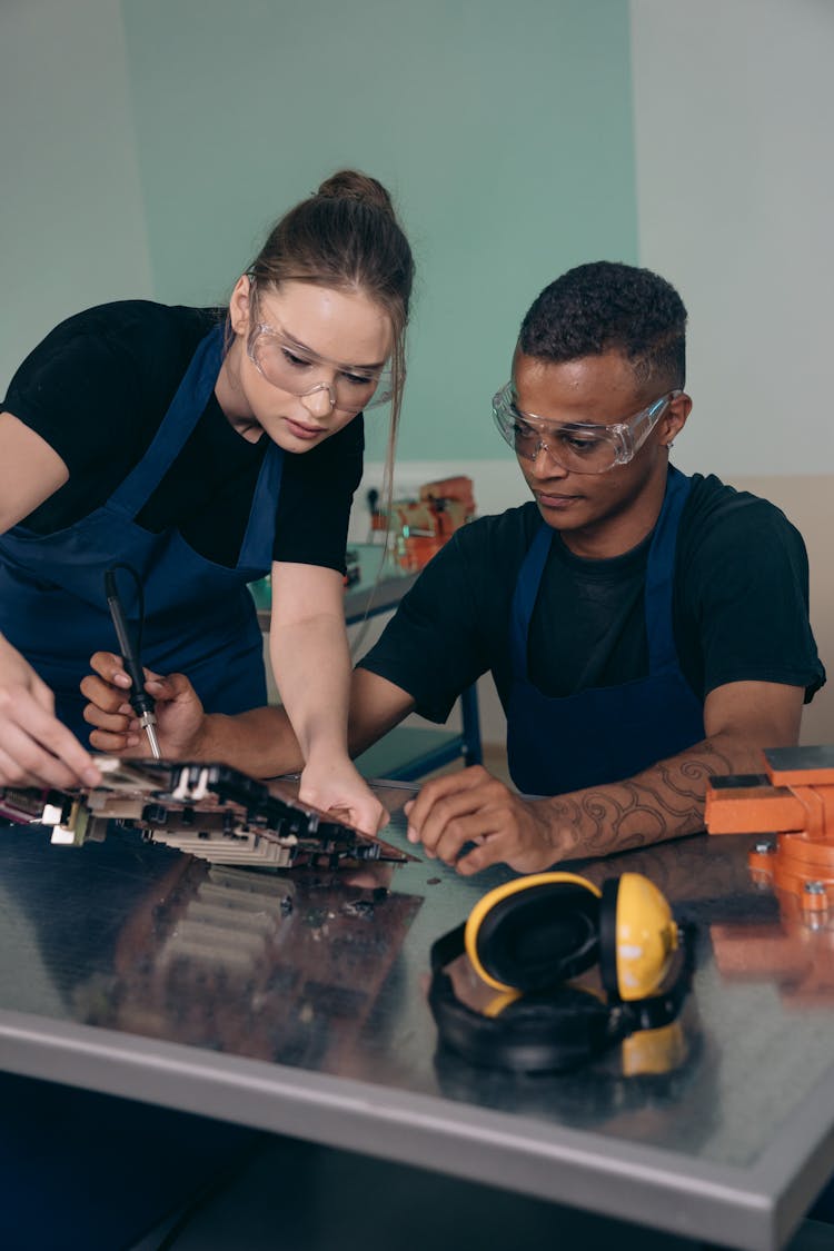 A Woman And Man Fixing An Electronic