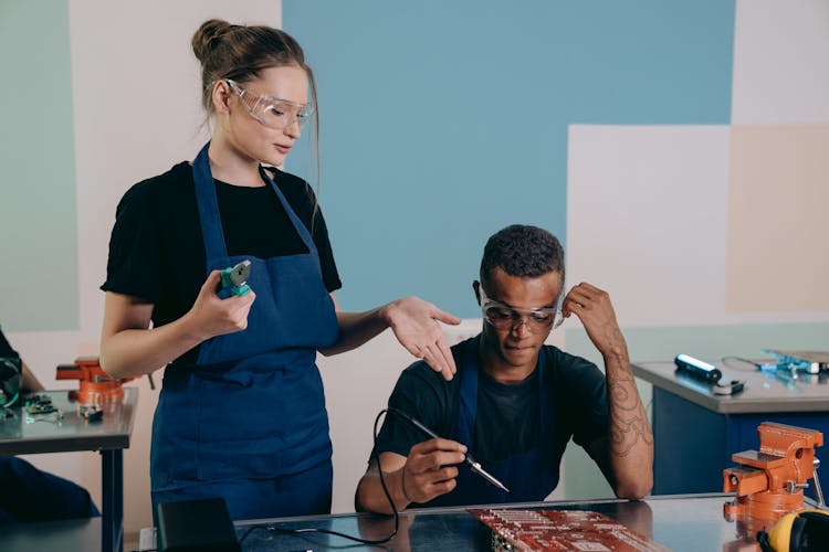 A Woman And Man Repairing An Electronic