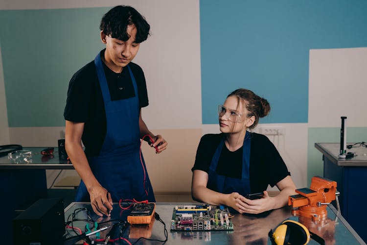 A Woman And Man Fixing An Electronic