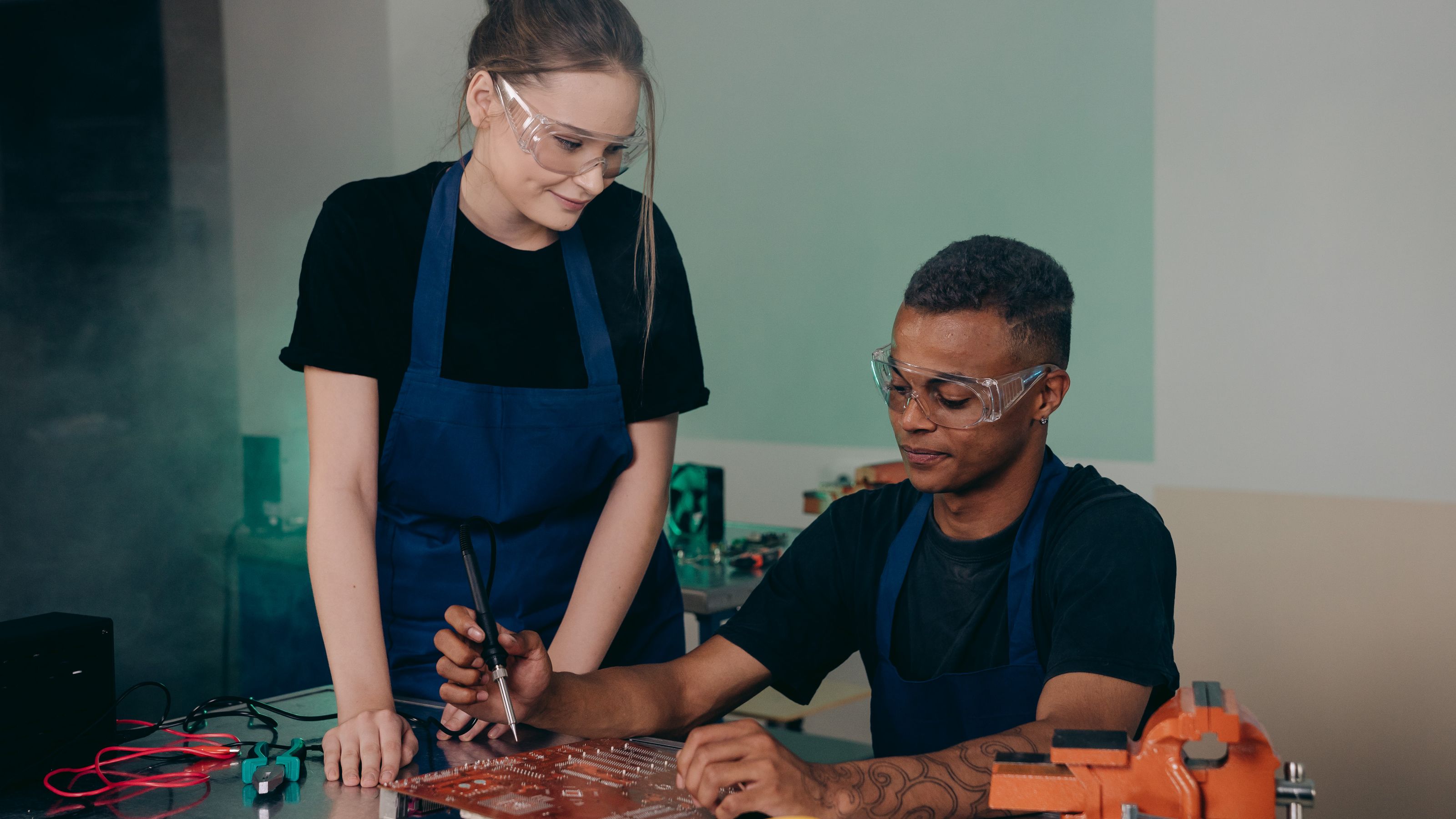 Two engineers checking a circuit board in a workshop