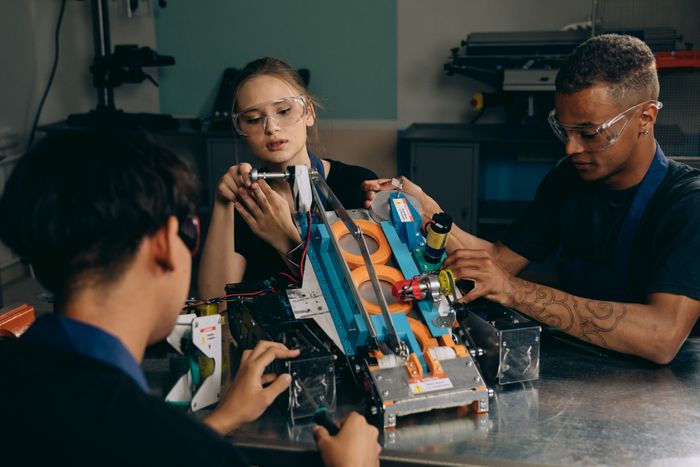 Engineers assembling a robotic device in a workshop, photo by Mikhail Nilov on Pexels