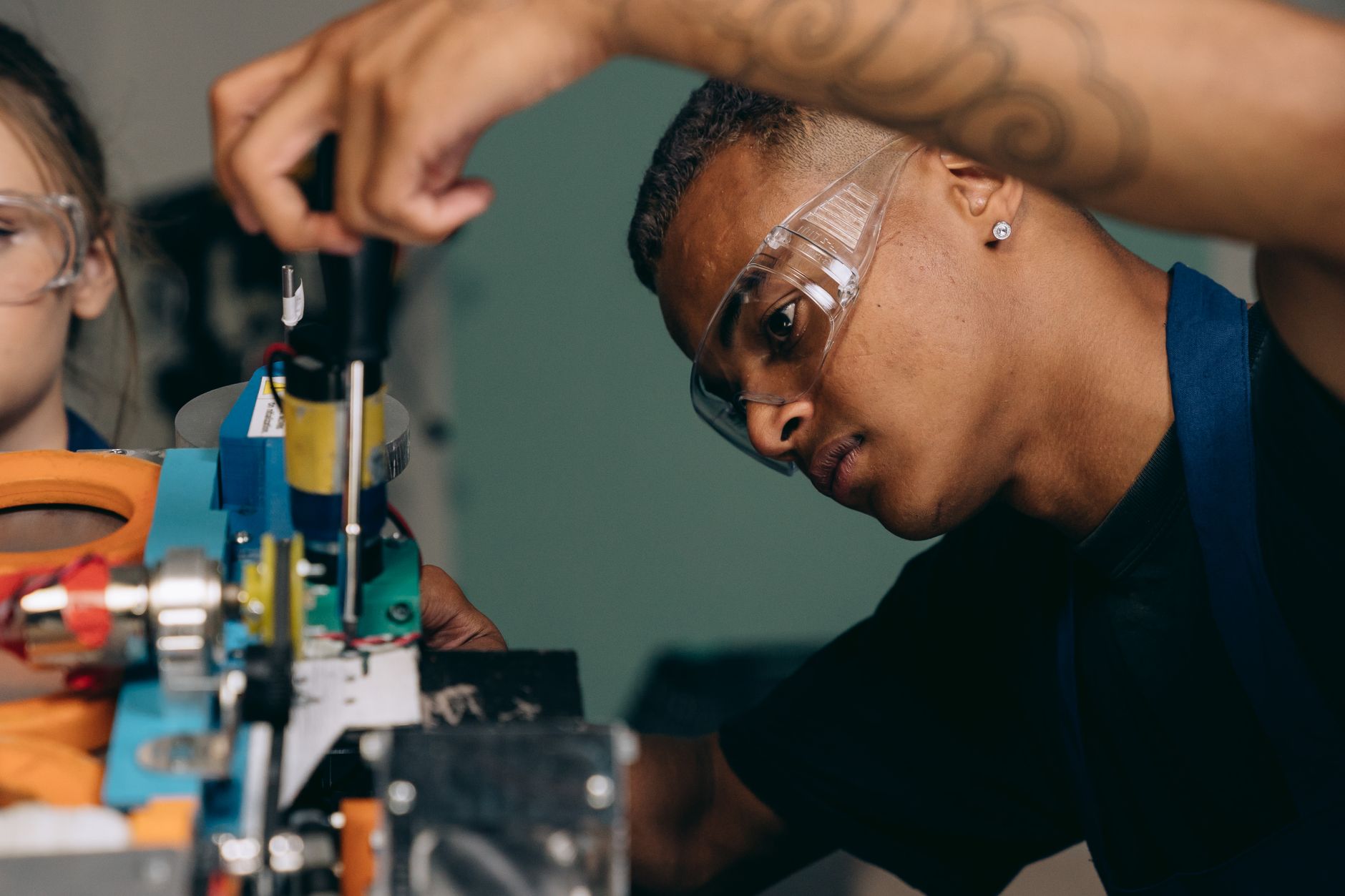 Two young technicians focus on electronic equipment assembly in a workshop setting.