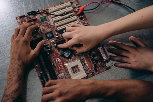 Close-up of hands repairing a motherboard, highlighting teamwork and electronics engineering.