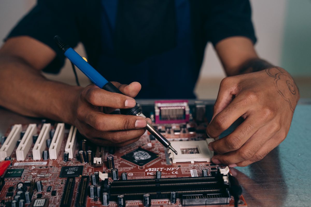 Technician soldering components on a computer motherboard