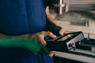 Close-up of technician using a handheld control device in a manufacturing setting.