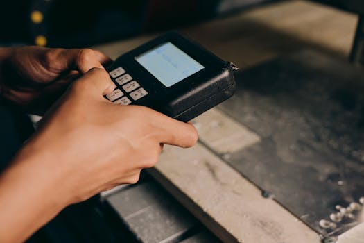 A detailed close-up of hands operating an electronic control device, capturing the precision of modern technology use.