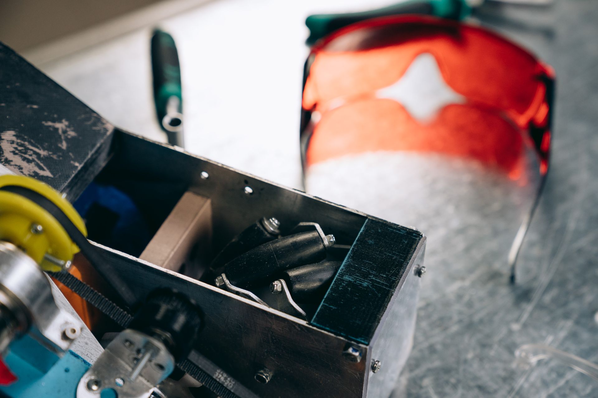 Close-up of industrial tools and safety glasses on a metal table, showcasing engineering elements.