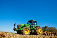 Green and Yellow Tractor on Brown Field Under Blue Sky