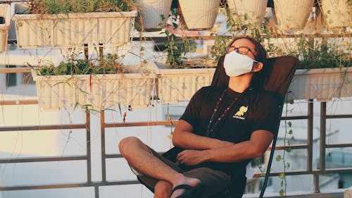 A Relaxed Man With Face Mask Sitting On A Chair